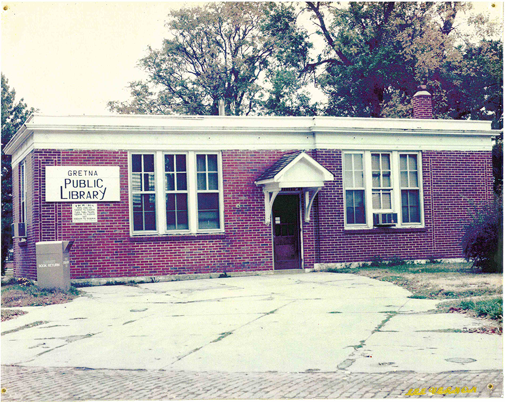 An exterior photo of the original Gretna Public Library (Nebraska) circa 1980. Old brick library building with an exterior book drop.