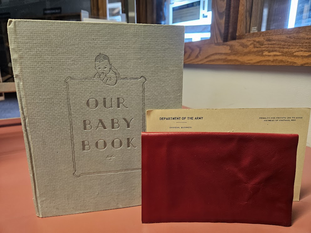 A baby book, a graduation diploma cover, and a letter from the Department of the Army.