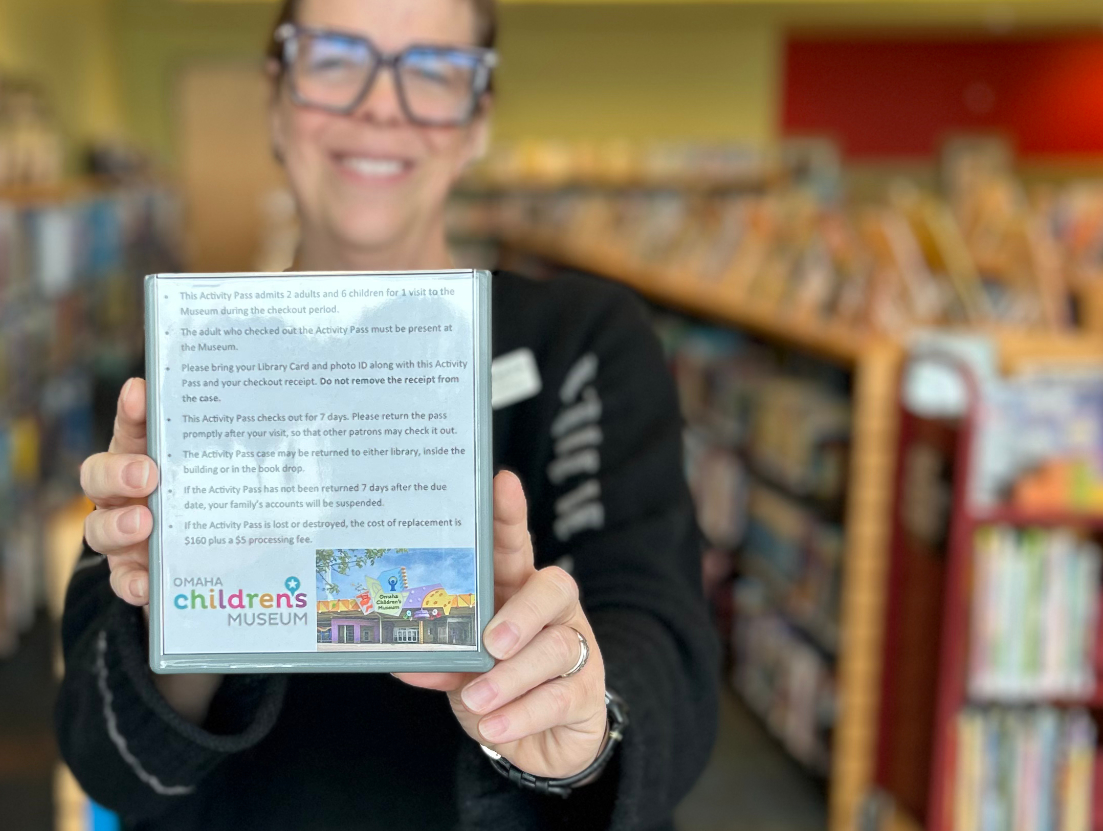 Librarian holds an Omaha Children's Museum library pass.