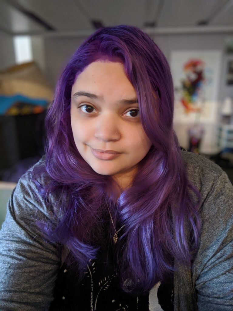 A librarian with purple hair and an anatomical heart necklace.